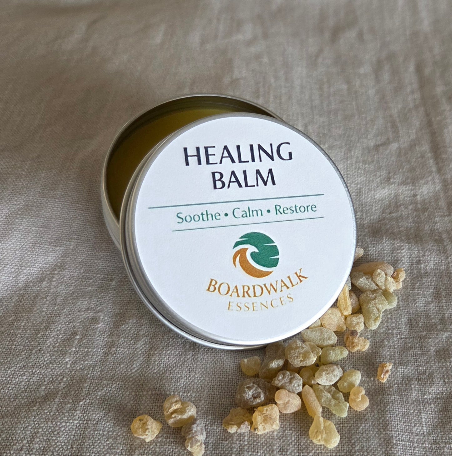 Healing Balm 50g aluminium tin with cream label and gold border arranged with gentle botanical elements