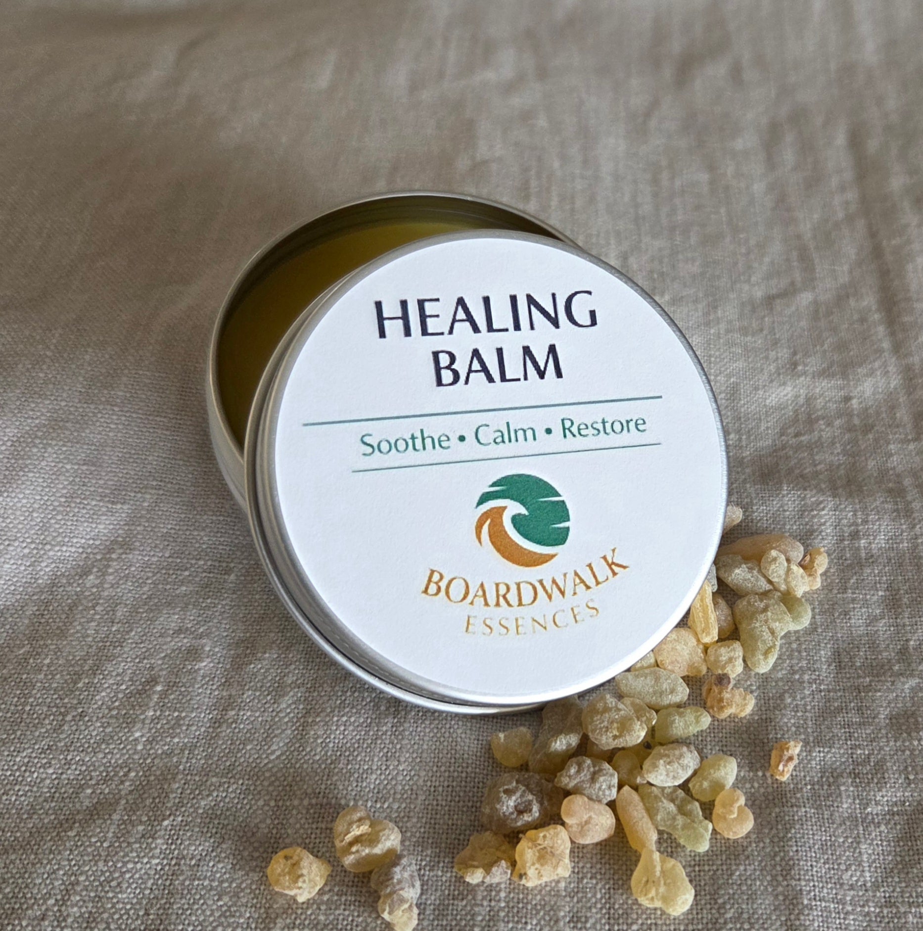 Healing Balm 50g aluminium tin with cream label and gold border arranged with gentle botanical elements
